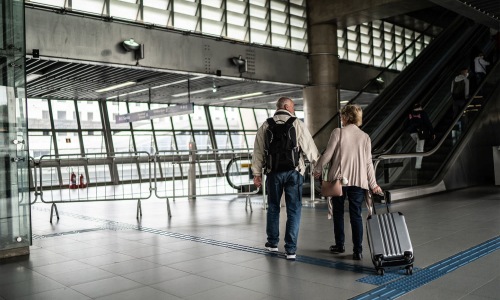 a man and a woman walking with luggage through an airport